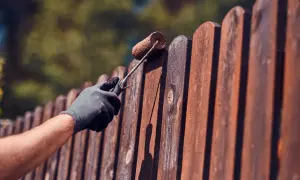 Aplicando protector a la valla de madera para saber como tratar la madera para que no se pudra.
