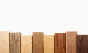 Bloques de madera dura de diferentes tonos y texturas, dispuestos en fila sobre fondo blanco.