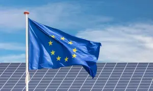 Bandera de la UE ondeando sobre placas solares en Extremadura, símbolo de ayudas para la energía limpia.